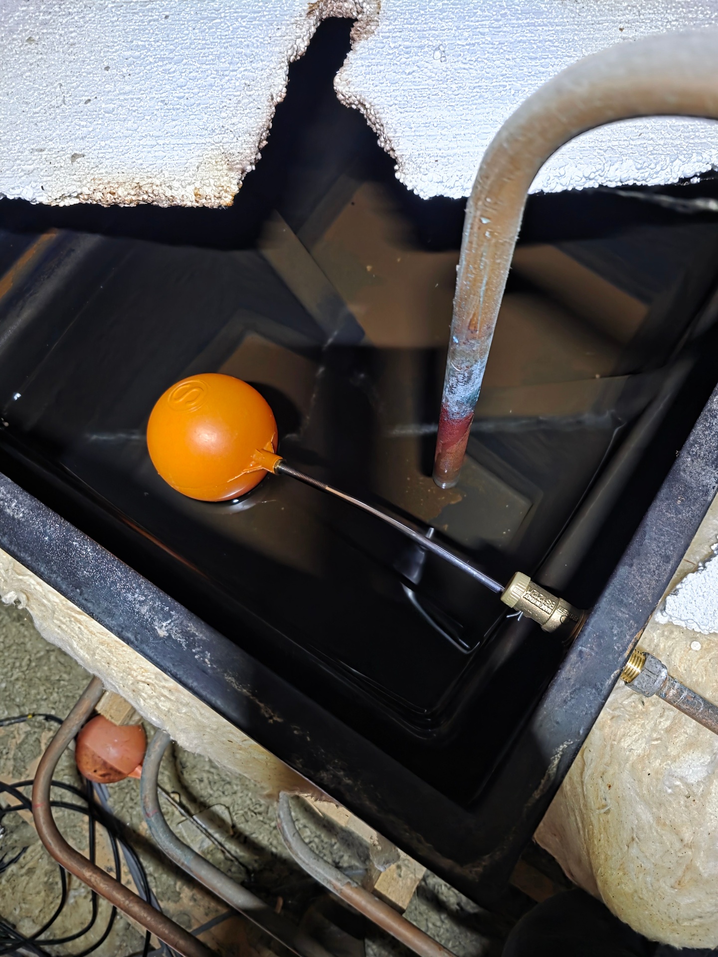 Cold water storage tank with float valve and insulated pipework in a loft