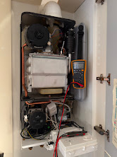Engineer testing a gas boiler with electronic diagnostic equipment during a breakdown call