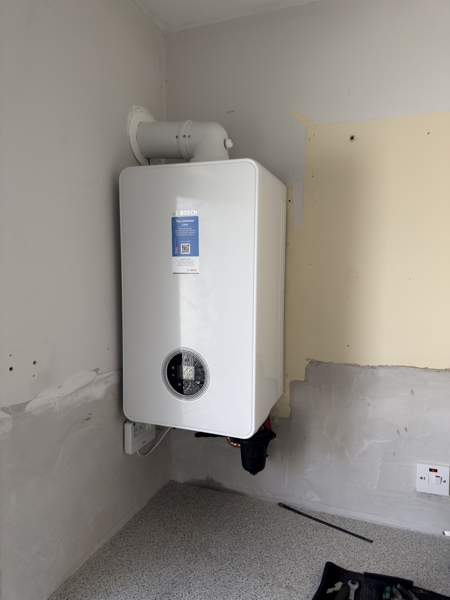 Bosch gas boiler installed in a utility room with new flue and room controls